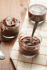 Creamy french chocolate ganache or pudding in glass on linen napkin on wooden background, three glasses
