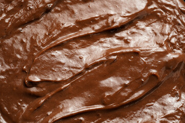 a close-up on chocolate ganache or pudding with swirls and spreads filling the frame, selective focus