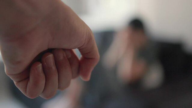 Clenched fist against the background of a crying woman. domestic violence concept