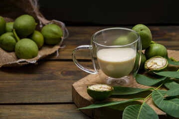 green walnut kernels leaves  wooden table oil nuts unripe husks healthy food drink, old rustic table Background Harvest, organic Homemade plant based milk Dairy free  jug glass cup