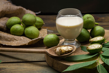 green walnut kernels leaves  wooden table oil nuts unripe husks healthy food drink, old rustic table Background Harvest, organic Homemade plant based milk Dairy free  jug glass cup