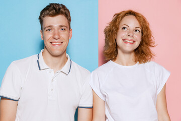 Portrait of beautiful young couple, man and woman smiling at camera, posing isolated over pink blue studio background