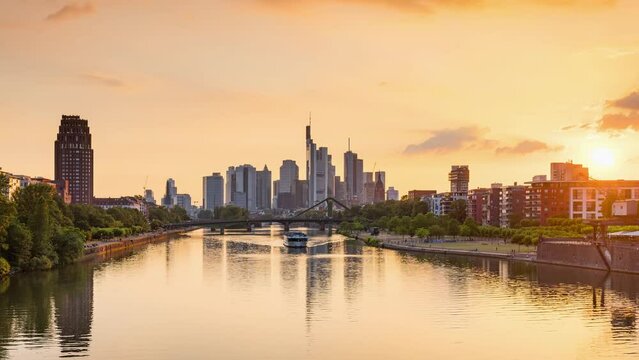 Day to Night Frankfurt skyline time lapse, blue sky with clouds, office buildings and skyscraper in center with river and bridges in the foreground, Frankfurt am Main, Hessen, Germany