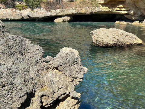 Scenic rocky coast of the sea. Cliff against clear turquoise sea water in paradise lagoon.
