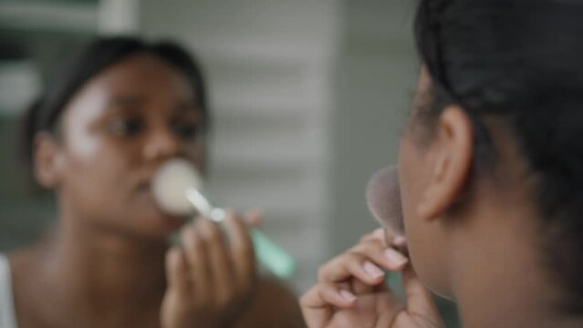 African-American woman applying make up blusher in the bathroom. Shot with RED helium camera in 4K.      