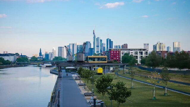 Frankfurt skyline hyperlapse time lapse, blue sky with clouds, office buildings and skyscraper in center with river and bridges in the foreground, Frankfurt am Main, Hessen, Germany