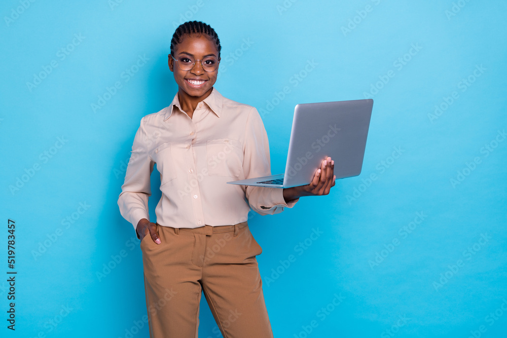 Wall mural photo of young reliable business lady working on new project holding wireless laptop isolated on blu