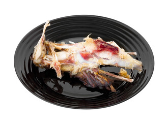 Chicken carcass on a black plate. Chicken bones.
