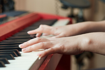 Obraz premium Close-up side view of a woman's hand playing a red electronic piano