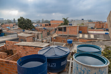 Naklejka premium Jardim Pantanal, São Paulo, SP, Brazil, JUL 27, 2022, Drums of water accumulated on the terrace of houses in the poor community