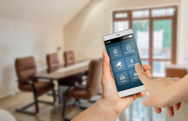 Woman using smart home application on mobile phone to control office devices