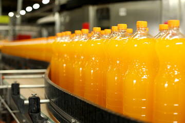 Production of carbonated drinks. Orange bottles on the production line.
