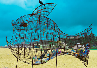 Fish-shaped Dustbin made from discarded metal sticks to collect garbage on the beach. Eco concept