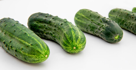 Ripe fresh green cucumbers laid out in a row, highlighted on a white background. A young summer harvest, vitamins and proper healthy nutrition