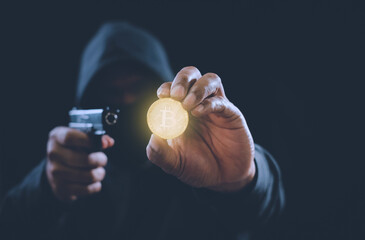 Bitcoin digital crypto currency is in hand of anonymous hacker holding gun in the shadows.