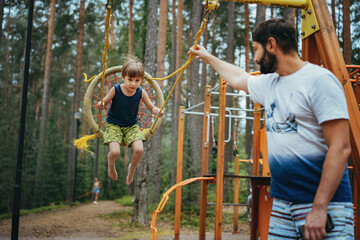 cute little boy having fun on a swing at playground.