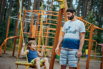 Fototapeta premium cute little boy having fun on a swing at playground.
