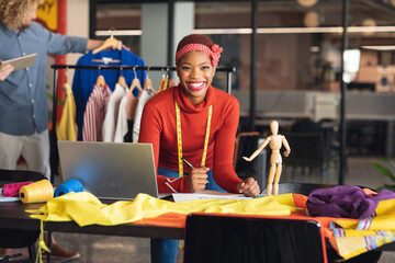 Portrait of happy african american fashion designer at desk in studio office