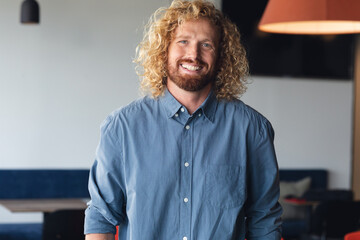 Portrait of smiling young caucasian businessman in creative office, copy space