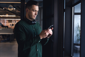 Caucasian young businessman text messaging through mobile phone in creative office