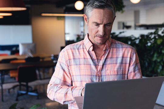 Caucasian mature businessman using laptop in creative office