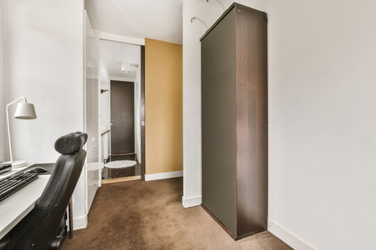 Room with a closet near a table with a chair and a computer