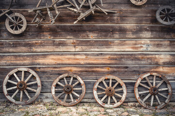 Fototapeta na wymiar Wooden house wall and ancient wagon wheels, tools and stuff