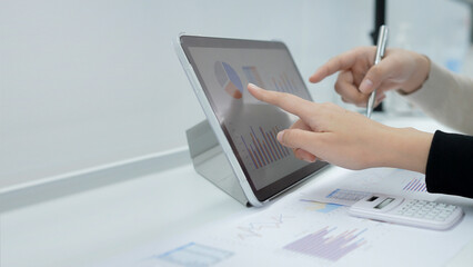 close up businesswoman hand point on dashboard screen tablet device for ask and consulting with businessman partner for kpi and investment concept