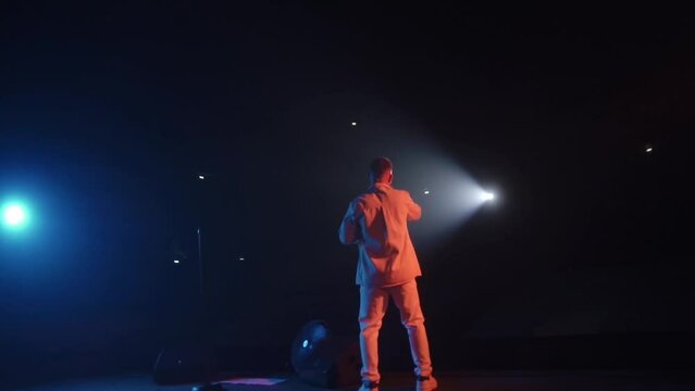 Blurred footage of Man singing to microphone. Unrecognisable person, Pop singer on stage club. Party concept, have fun tonight. Neon lighting flickering on the event.