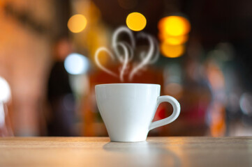 Obraz premium Hot Coffee Cup on Wood Table in blurred Coffee Shop background.