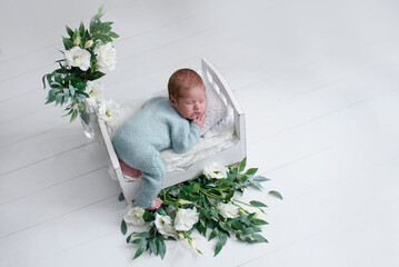 A cute newborn is lying in bed. baby sleep dressed in a blue knitted suit