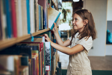 Schoolgirl choosing book in school library. Smart girl selecting literature for reading. Learning from books. Benefits of everyday reading. Child curiosity. Back to school - 519796062