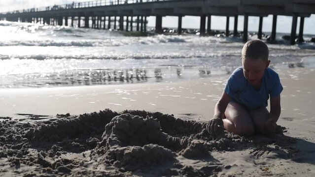 Boy playing with sand at beach in Palanga, Lithuania. Building castle