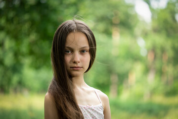 Portrait of beautiful preteen girl in forest on summer sunny day