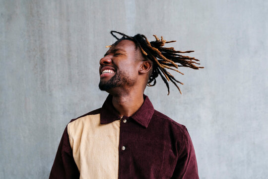 Happy man tossing hair in front of wall