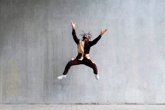 Cheerful man jumping in front of concrete wall