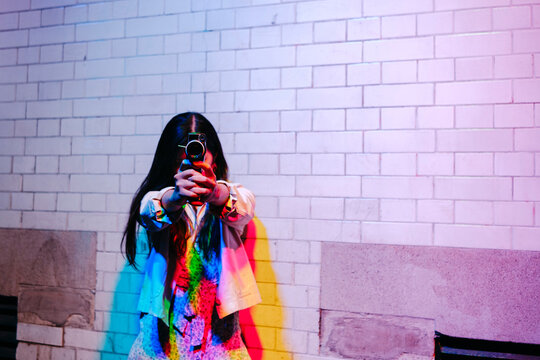 Woman with video camera standing in front of wall
