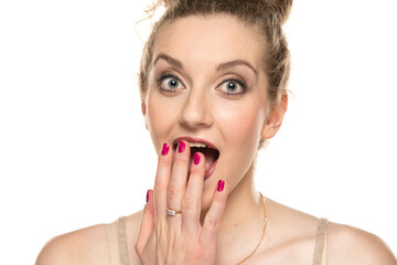 Fototapeta premium Young blond surprised woman with curly tied hair and makeup posing on white background