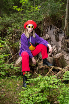 Woman wearing sunglasses sitting on tree stump