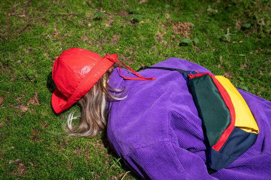 Woman wearing red bucket hat lying in forest