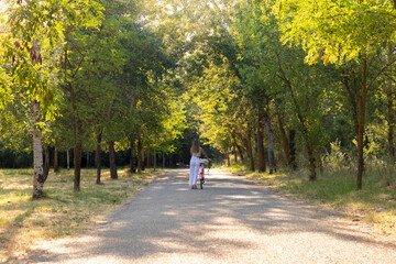 Far view of young woman alone carrying a bicycle on her side sorrounded by natural enviroment