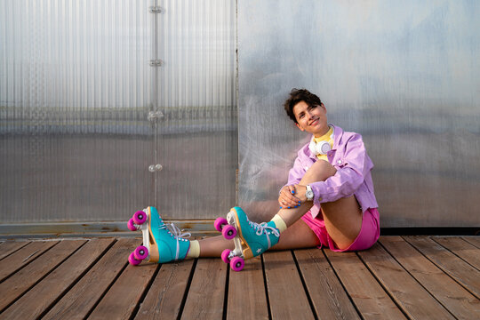 Thoughtful woman with roller skates sitting on footpath
