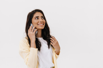 Young brunette indian woman smiling while using cellphone