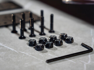 CLOSE UP: Lined up assortment of nuts, bolts and Allen key on gray countertop