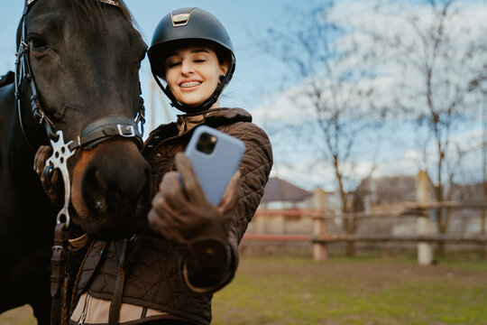 Jockey woman taking selfie with her horse during equestrian practice