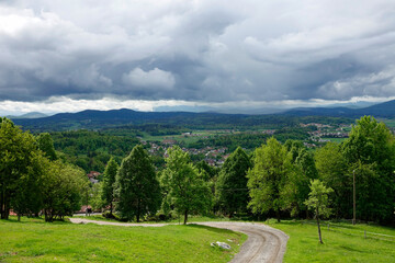Fototapeta na wymiar Beautiful view macadam path and hilly countryside with rolling gray storm clouds