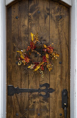Heavy wooden door decorated with a wreath for the Autumn season