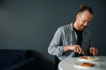 Young man having breakfast while sitting at table at home