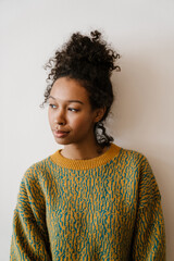 Black young woman wearing sweater posing and looking aside