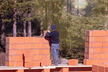 The builder erects a brick wall. Bricklaying. Bricklayer builder, private master. Construction of a cottage, a country house.